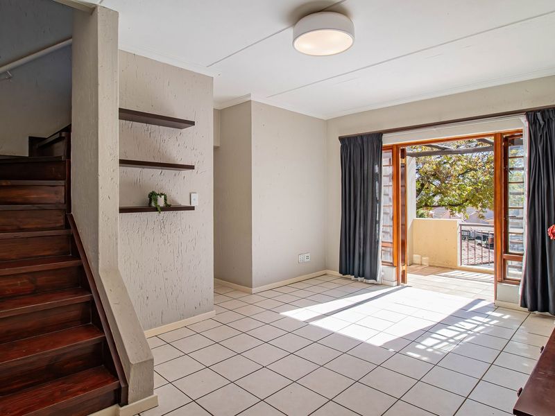 Bright living area featuring a wooden staircase, tiled flooring, and sliding glass doors leading to an outdoor balcony space.