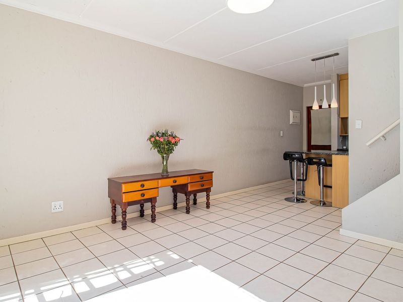 Open plan living area featuring tiled flooring, a breakfast bar with pendant lighting, and an adjacent staircase with built-in wall shelving.