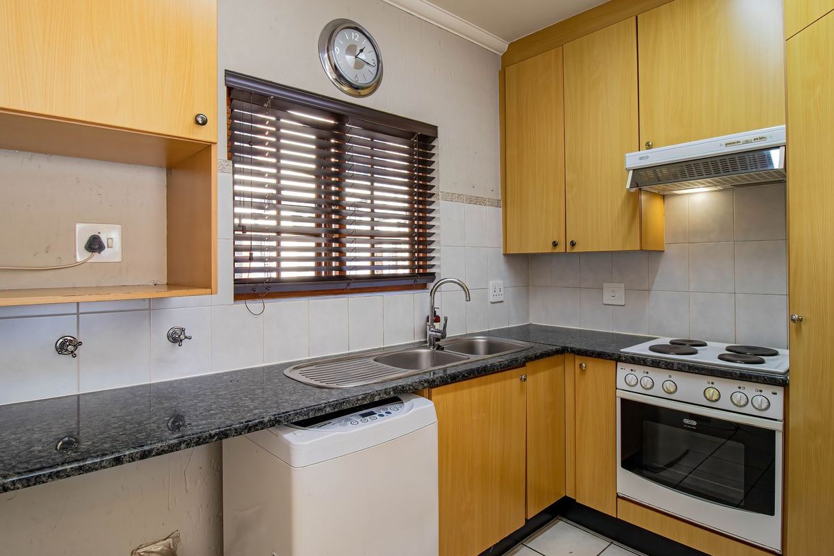 A functional kitchen featuring laminate cabinetry, granite countertops, a built-in oven with hob, and a tiled backsplash with a window view.
