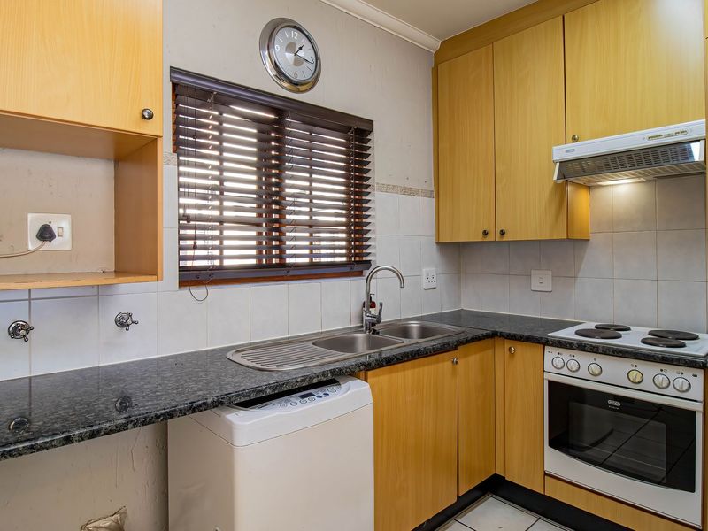 A functional kitchen featuring laminate cabinetry, granite countertops, a built-in oven with hob, and a tiled backsplash with a window view.