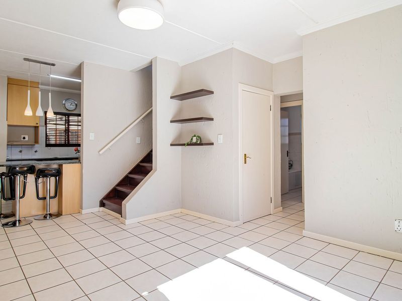 Open plan living area featuring tiled floors, a staircase, and an integrated kitchen with a breakfast bar and built-in cabinetry.