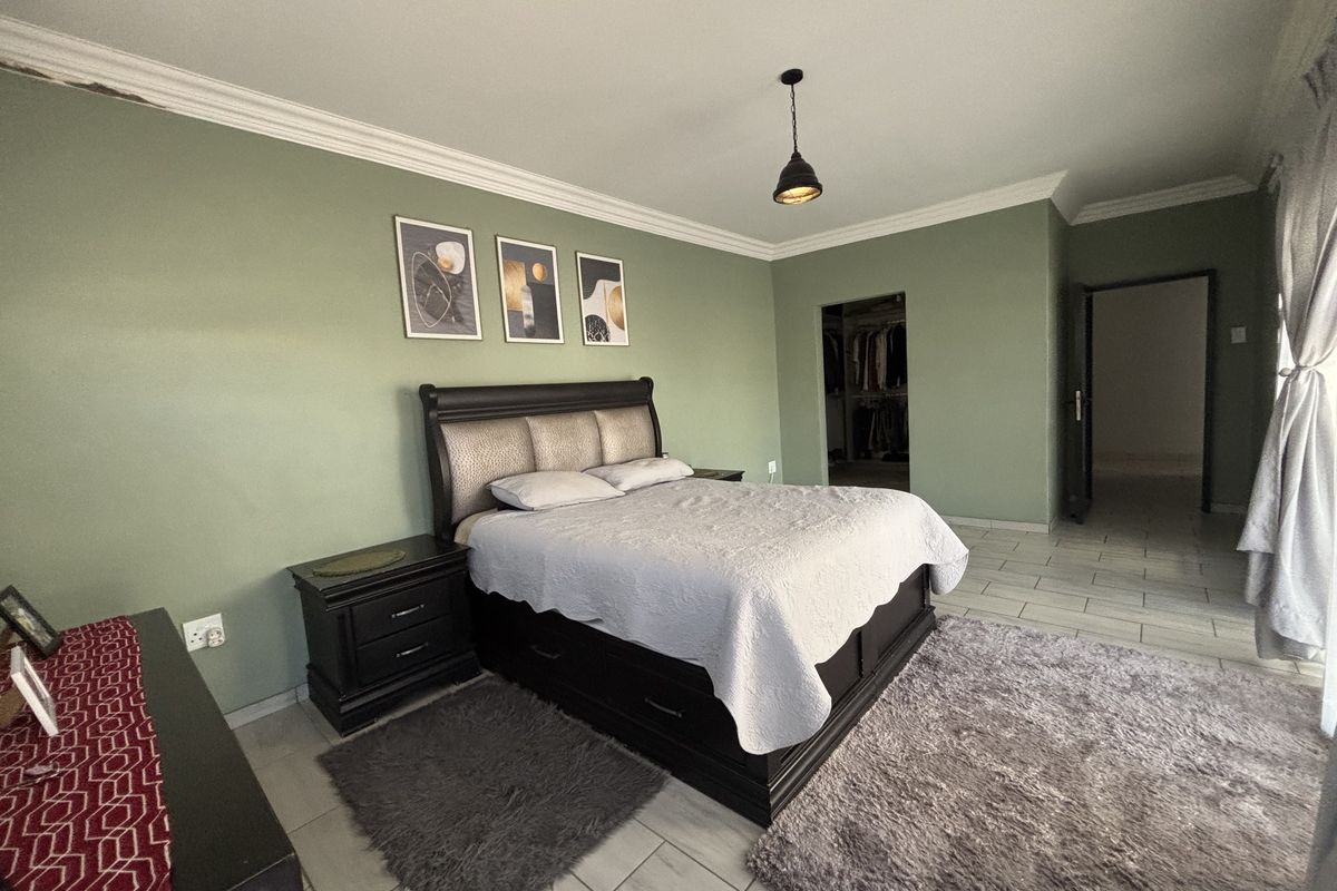 Spacious bedroom featuring tiled flooring, a walk-in closet, and decorative cove cornicing, offering a comfortable and functional living space.