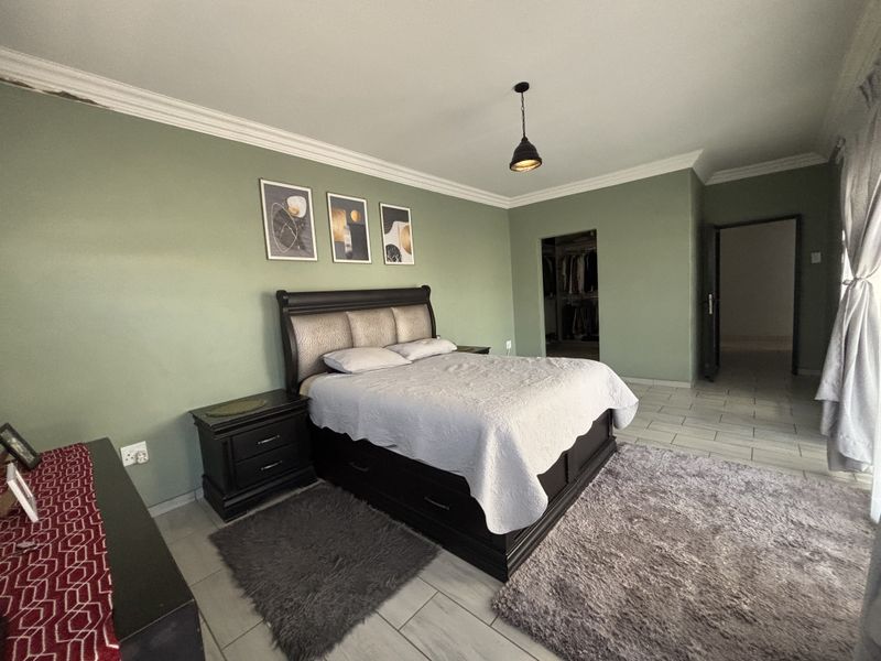 Spacious bedroom featuring tiled flooring, a walk-in closet, and decorative cove cornicing, offering a comfortable and functional living space.