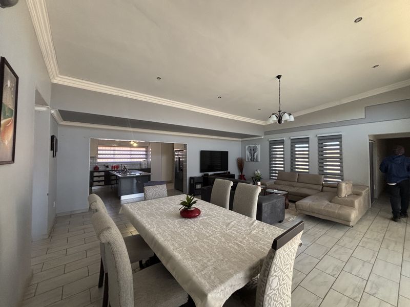 Spacious open-plan living and dining area featuring tiled floors, crown molding, and a seamless transition into a modern kitchen with a central island.