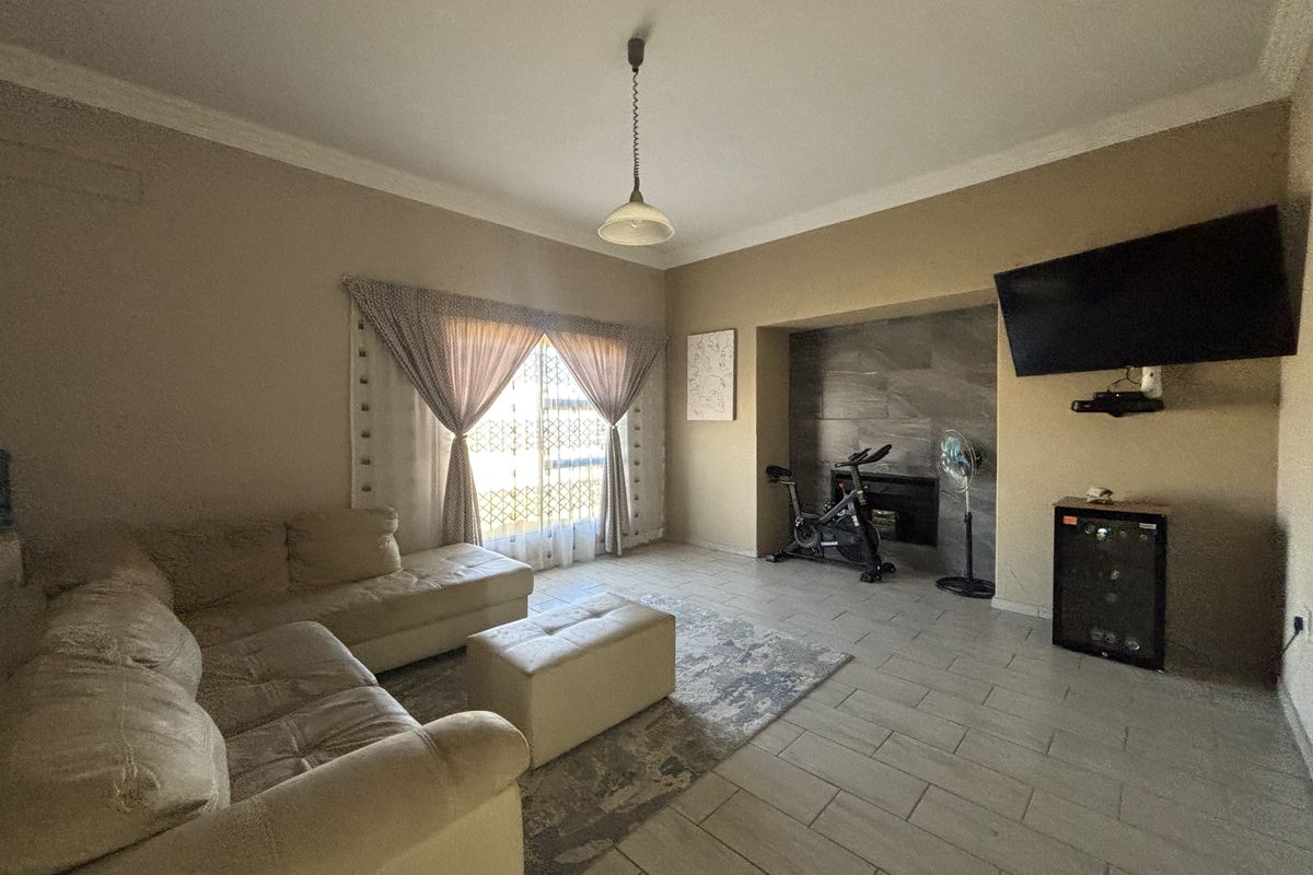 A spacious living room featuring tiled flooring, a stone-clad fireplace feature wall, and decorative cove cornicing.
