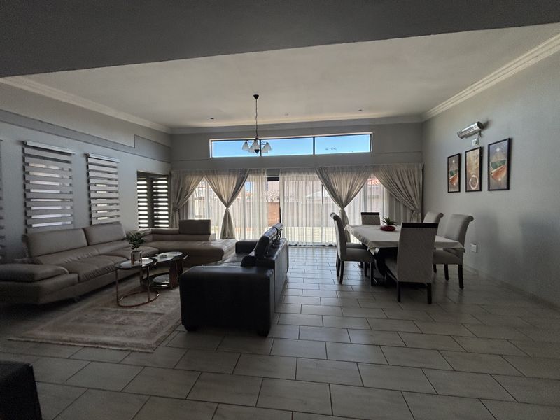 Spacious open-plan living and dining area featuring tiled flooring, high ceilings with cove cornicing, and large sliding doors leading to the exterior.