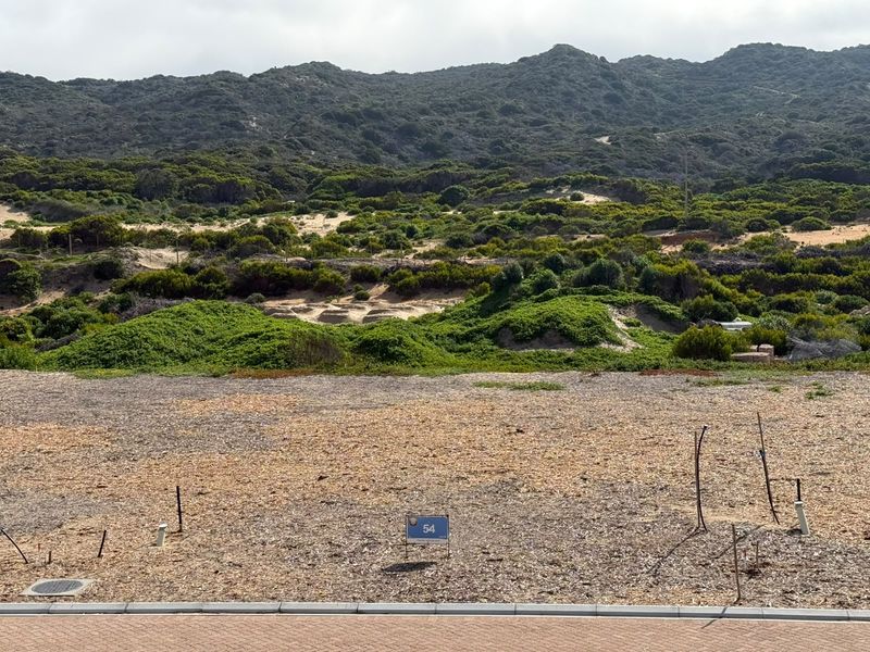A vacant residential plot featuring utility connection points and a scenic natural landscape backdrop.