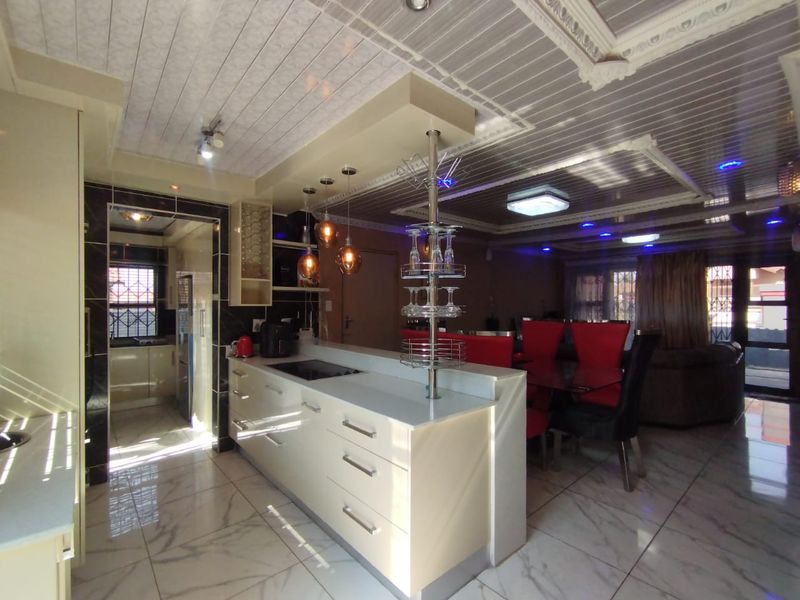Open-plan living and kitchen area featuring a central island, modern cabinetry, tiled flooring, and decorative ceiling finishes with integrated lighting.