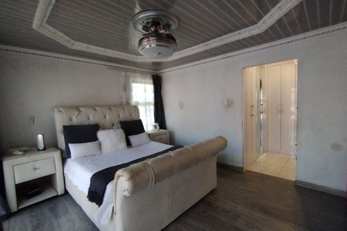 A bedroom featuring laminate flooring, a decorative ceiling with a fan, and an adjoining walk-in closet area with built-in cupboards.