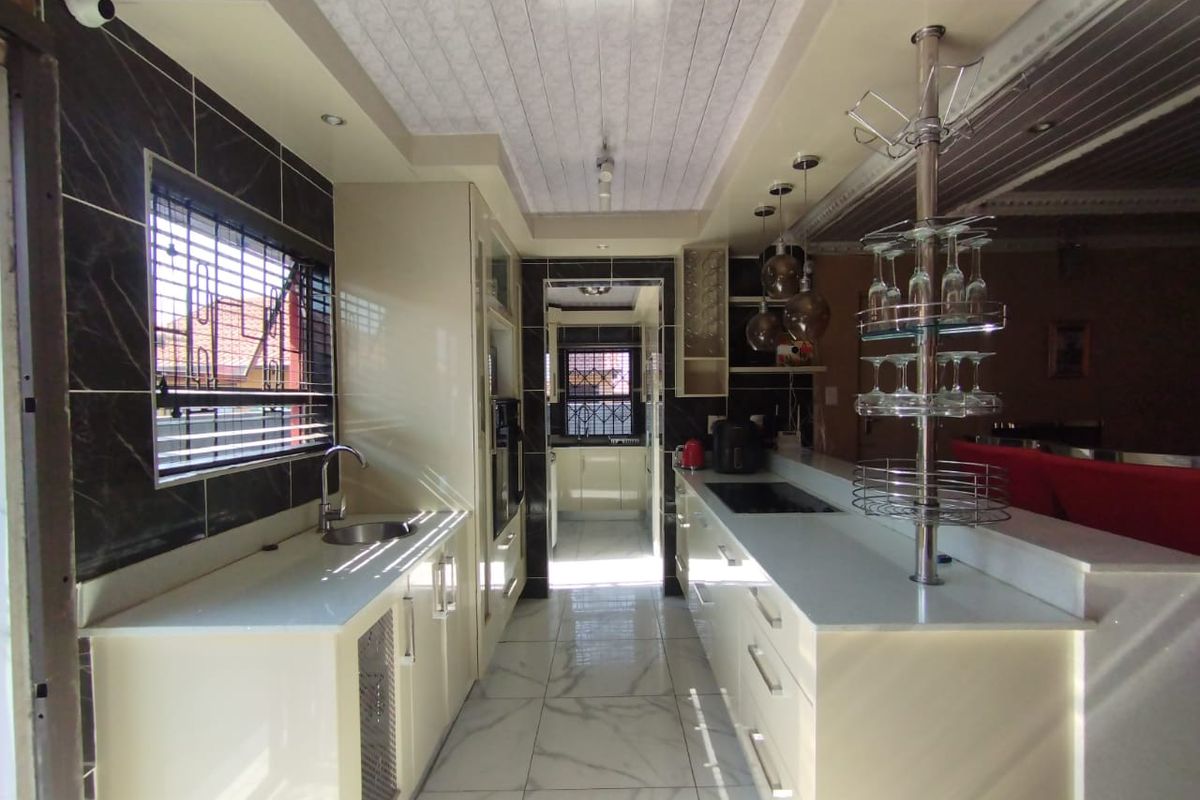 Modern kitchen featuring sleek cabinetry, stone countertops, integrated appliances, and polished tiled flooring with a functional layout and ample storage space.