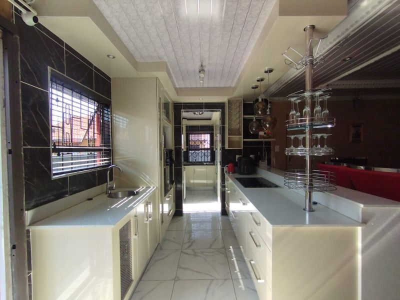 Modern kitchen featuring sleek cabinetry, stone countertops, integrated appliances, and polished tiled flooring with a functional layout and ample storage space.