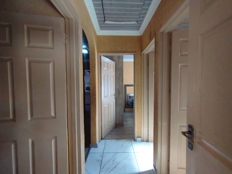 A central hallway featuring tiled flooring and multiple interior doors providing access to adjacent rooms within the home.
