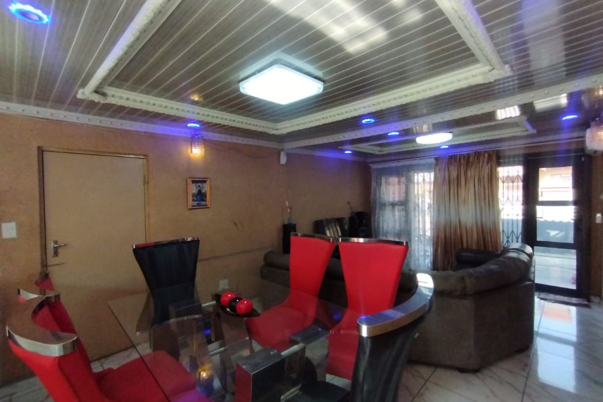 Living and dining area featuring tiled flooring, decorative ceiling panels with integrated lighting, and access to an outdoor space via a sliding glass door.