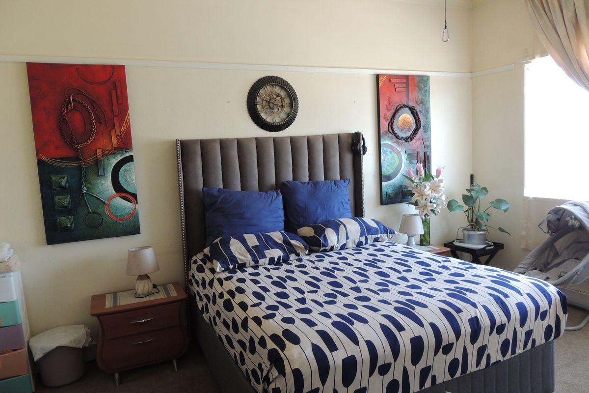 A bedroom featuring neutral walls, a picture rail, and a window with curtain fixtures.
