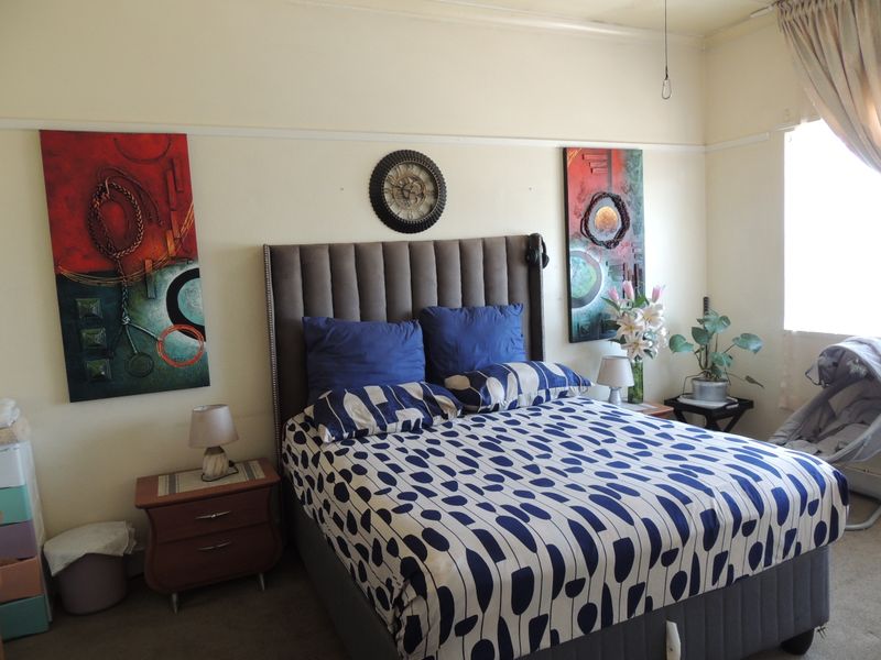 A bedroom featuring neutral walls, a picture rail, and a window with curtain fixtures.