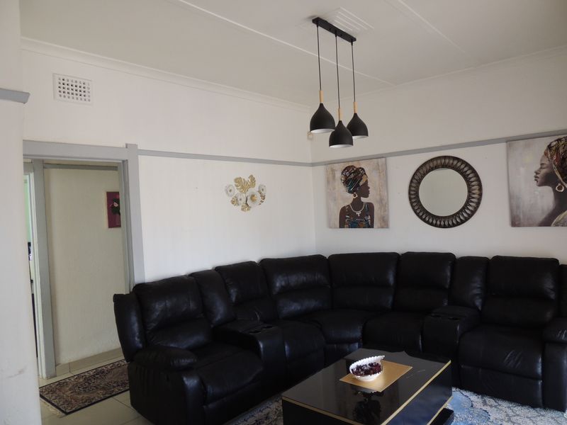 A comfortable living room featuring a picture rail, ceiling rose, and modern pendant lighting, providing a functional and well-maintained space.