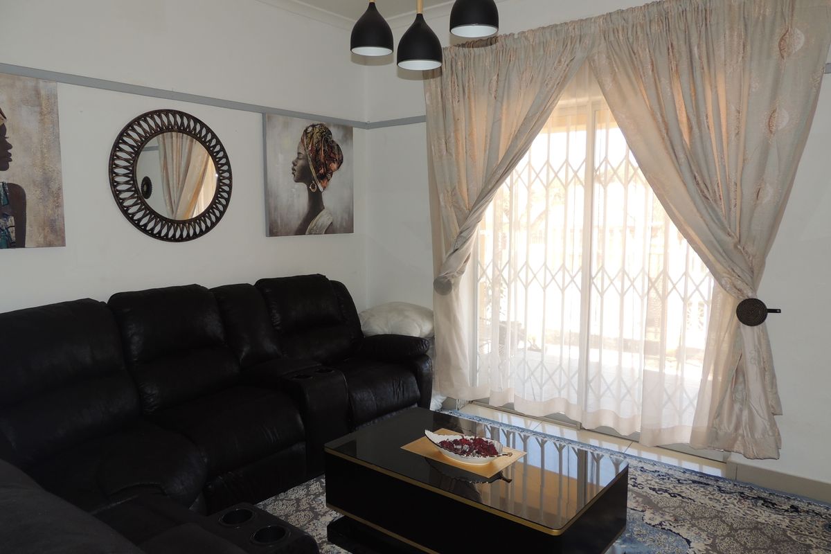 A comfortable living room featuring a sliding glass door with a security gate, pendant lighting, and classic picture rail detailing.
