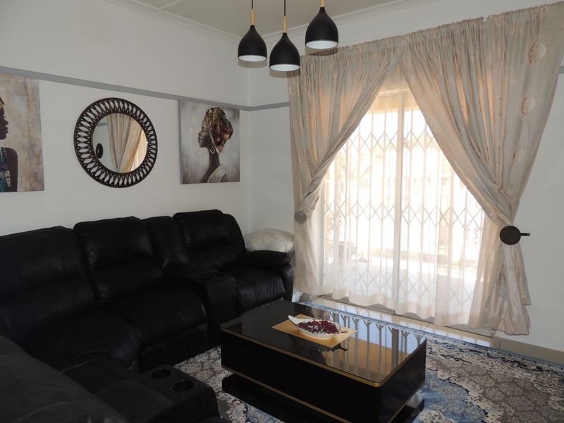 A comfortable living room featuring a sliding glass door with a security gate, pendant lighting, and classic picture rail detailing.