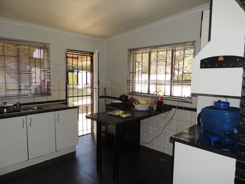 Functional kitchen featuring granite countertops, tiled backsplash, and direct access to the rear garden through a security gate.