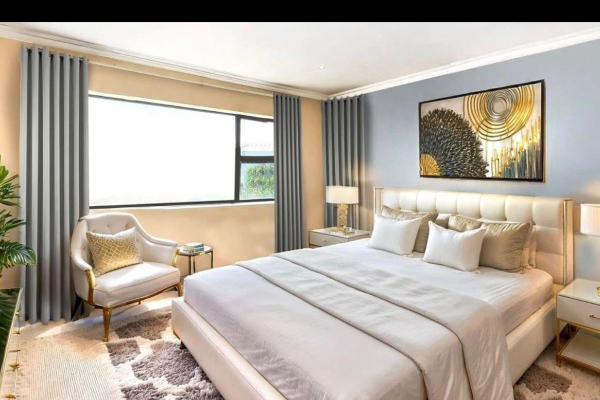 A well-appointed bedroom featuring a large window, neutral wall tones, and elegant ceiling detailing, creating a comfortable and inviting sleeping space.