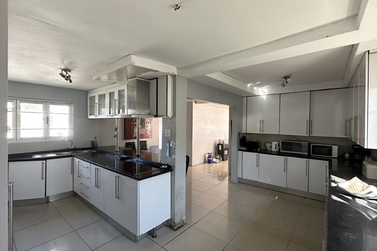 Spacious kitchen featuring white cabinetry, dark granite countertops, and tiled flooring, with an open-plan layout connecting to adjacent living areas.