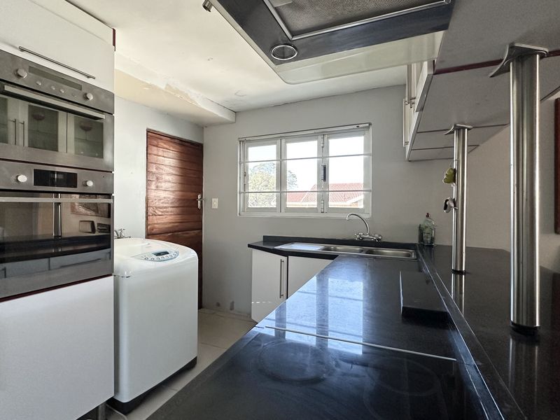 Functional kitchen featuring built-in oven and microwave, granite countertops, and stainless steel sink, with some minor cosmetic repairs needed to ceiling and wall finishes.