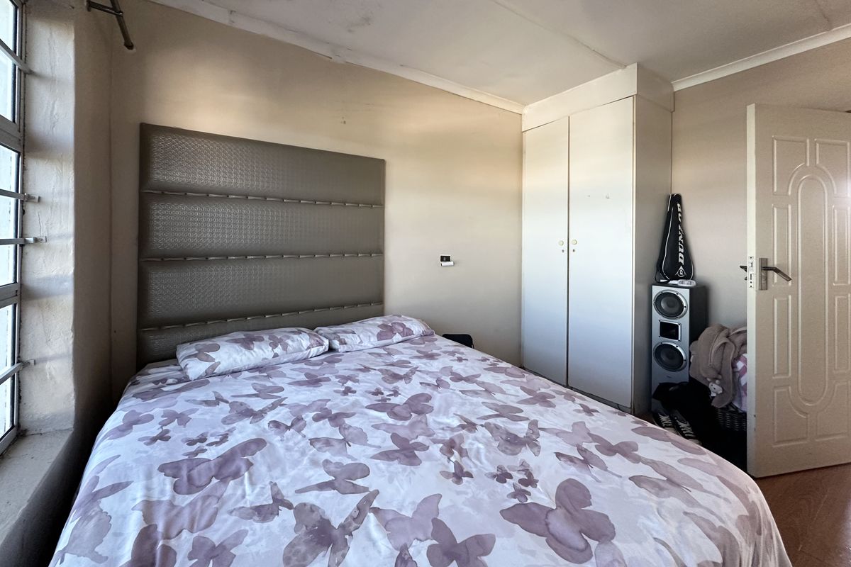 A bedroom featuring a built-in wardrobe and coved ceiling, showing signs of ceiling water damage and paint deterioration requiring maintenance.
