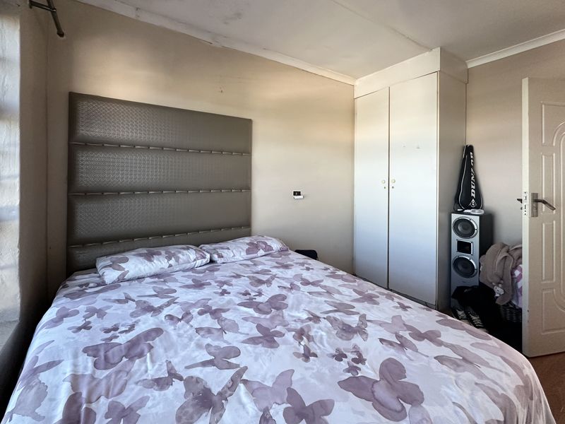 A bedroom featuring a built-in wardrobe and coved ceiling, showing signs of ceiling water damage and paint deterioration requiring maintenance.