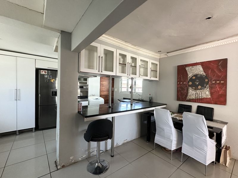 Open plan kitchen and dining area featuring a breakfast bar, tiled flooring, and built-in cabinetry with integrated appliances.