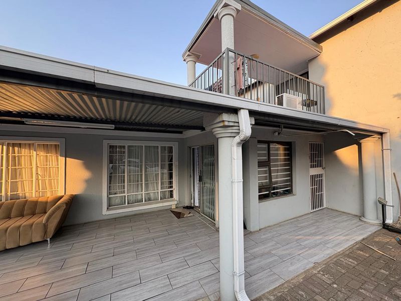 Covered ground-floor patio with tiled flooring and access to a second-story balcony with metal railings.