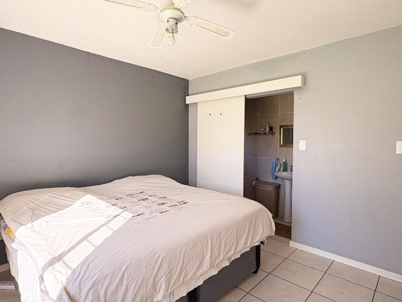 Bedroom featuring tiled flooring, a ceiling fan, and direct access to an en-suite bathroom via a sliding door.