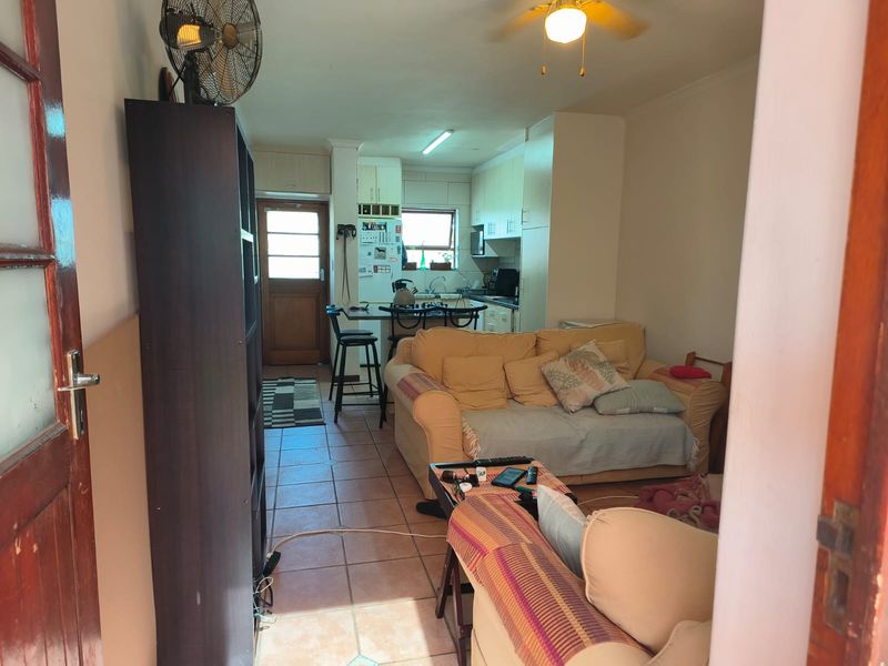 Open plan living and kitchen area featuring tiled flooring, functional cabinetry, and direct access to an exterior door.
