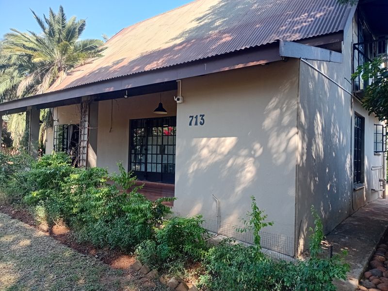 Front facade of a house featuring a corrugated metal roof, steel-framed glass entrance doors, and established garden landscaping.