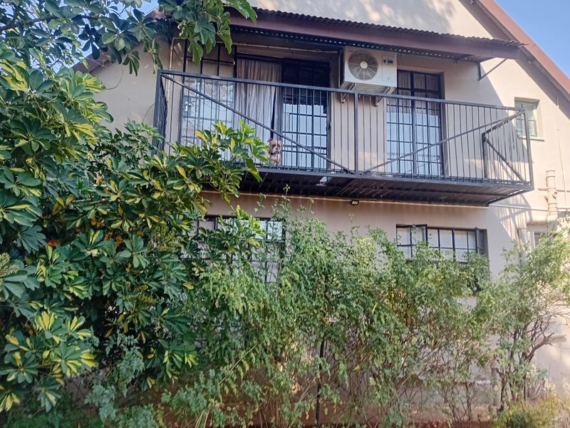 Rear exterior view of the property featuring a metal balcony with security bars and an installed air conditioning unit.