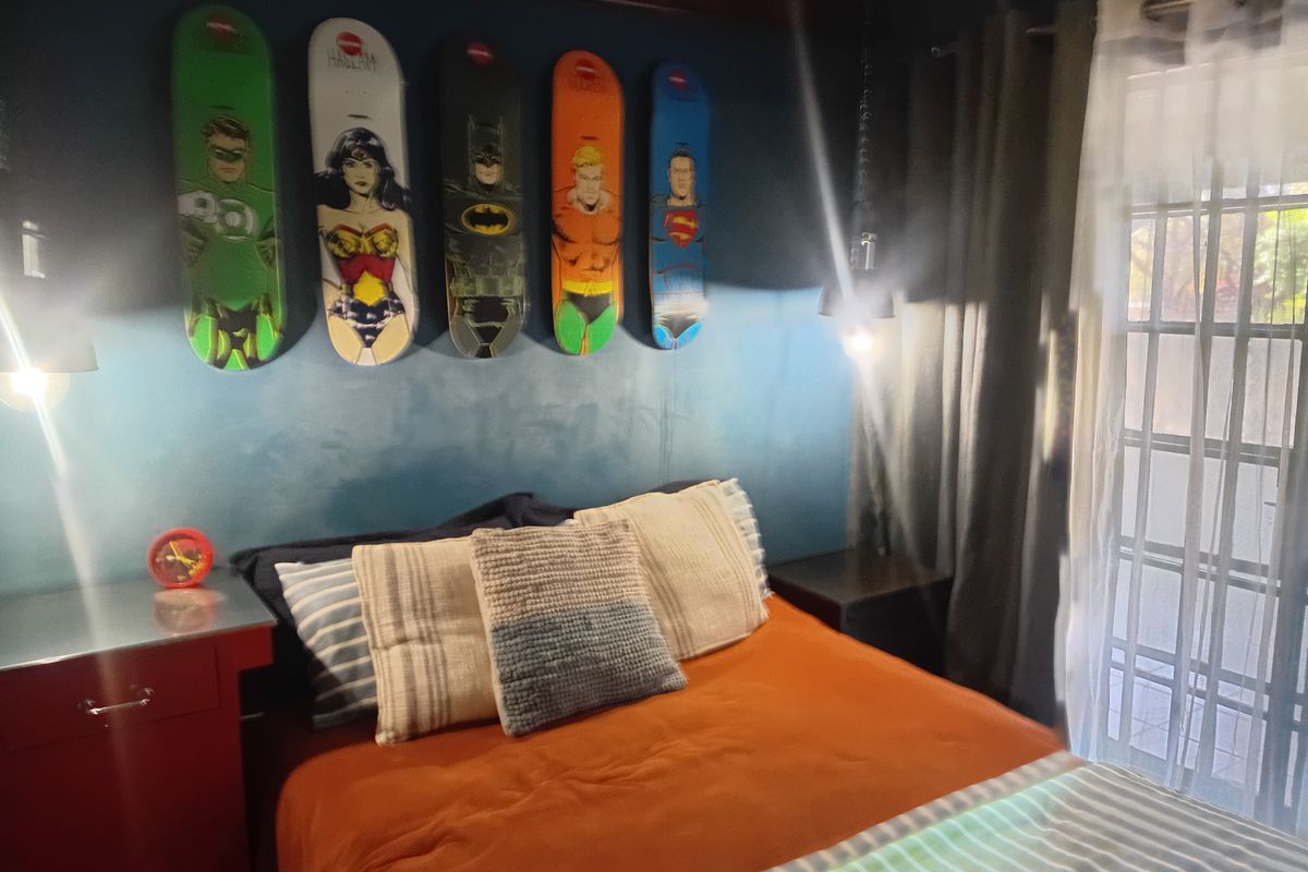 A bedroom featuring exposed timber ceiling beams and a sliding glass door with security gate providing access to the exterior.