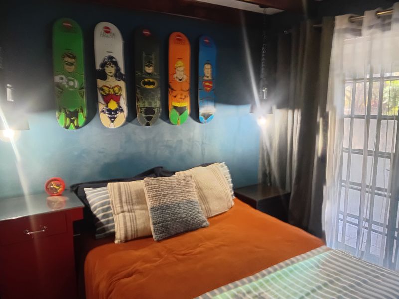 A bedroom featuring exposed timber ceiling beams and a sliding glass door with security gate providing access to the exterior.