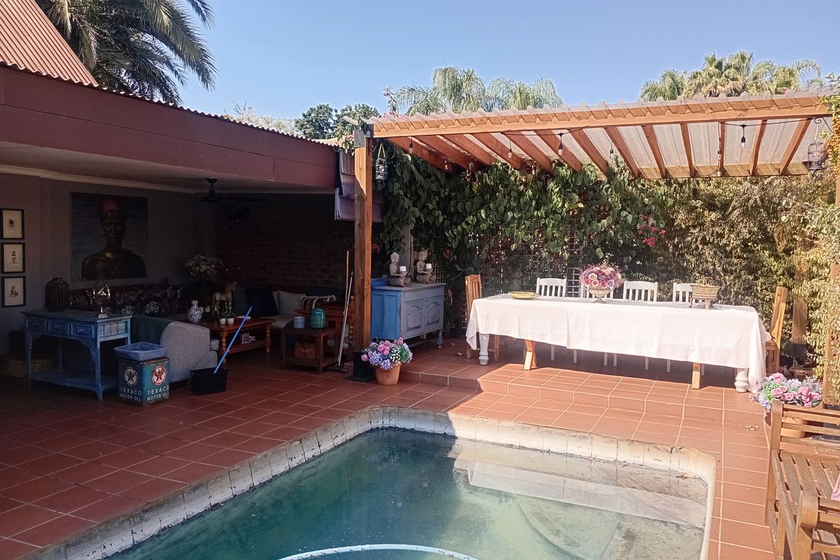 Outdoor entertainment area featuring a swimming pool, covered patio, and timber pergola, ideal for alfresco dining and relaxation.
