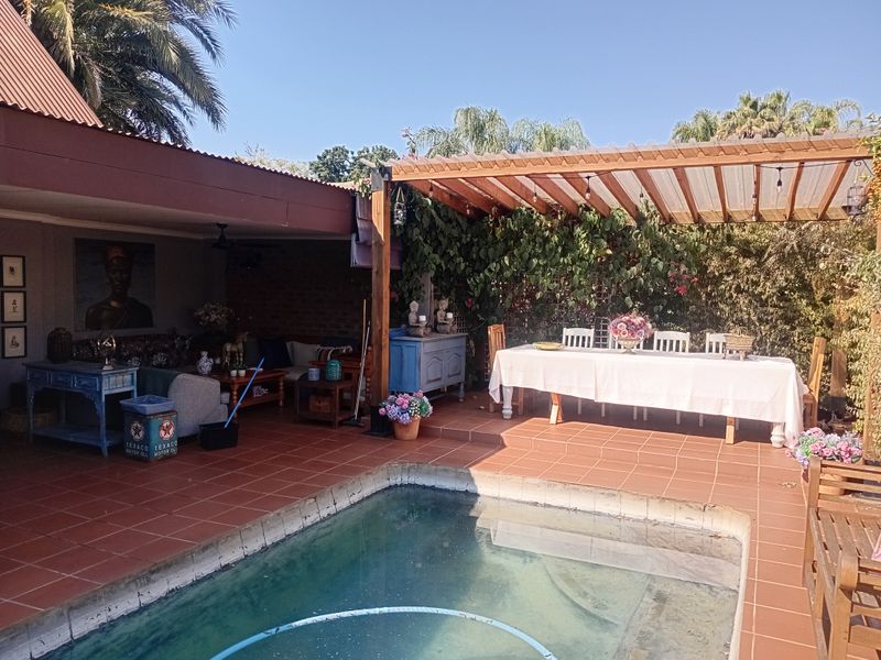 Outdoor entertainment area featuring a swimming pool, covered patio, and timber pergola, ideal for alfresco dining and relaxation.