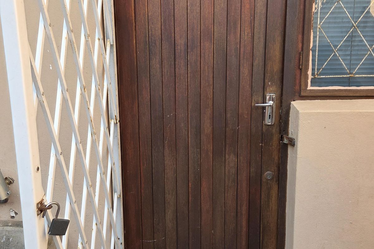 Entrance to unit 3 featuring a timber door, security gate, and window with security bars.
