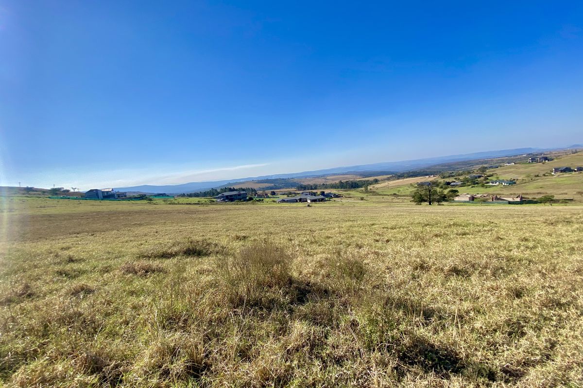 A wide-angle view of the vacant residential land, showcasing the expansive grassy terrain and surrounding landscape.