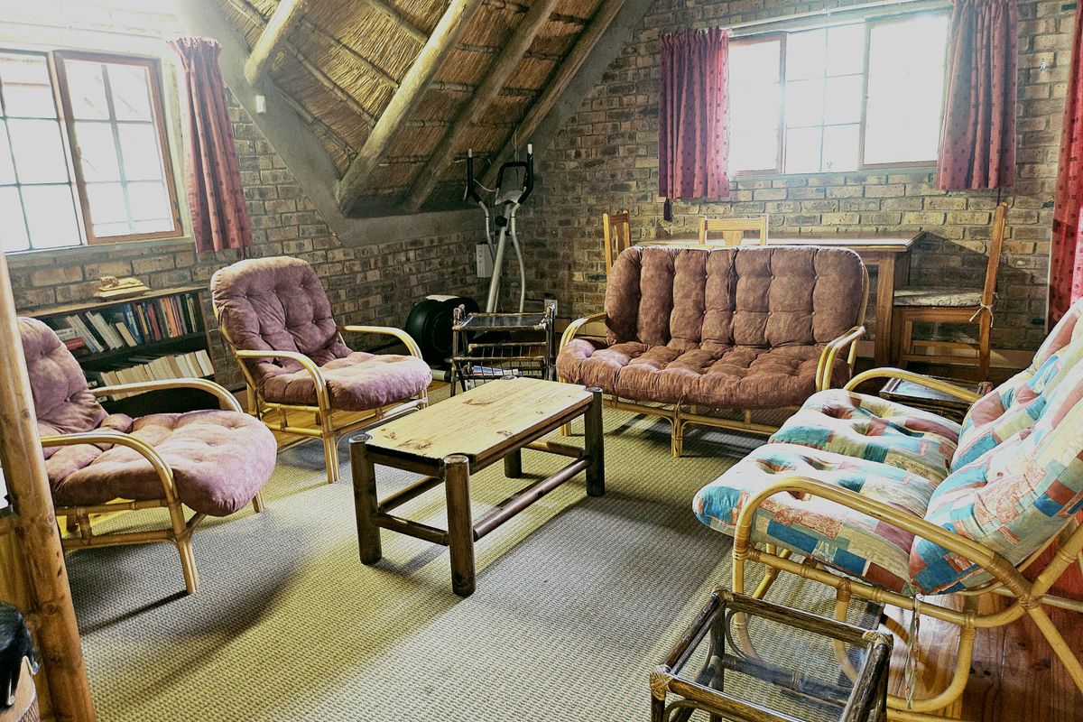 A rustic living room featuring exposed brick walls and a traditional thatched roof, creating a warm and character-filled atmosphere.