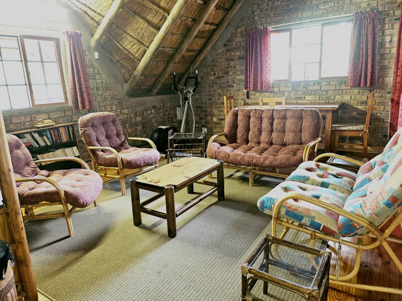 A rustic living room featuring exposed brick walls and a traditional thatched roof, creating a warm and character-filled atmosphere.