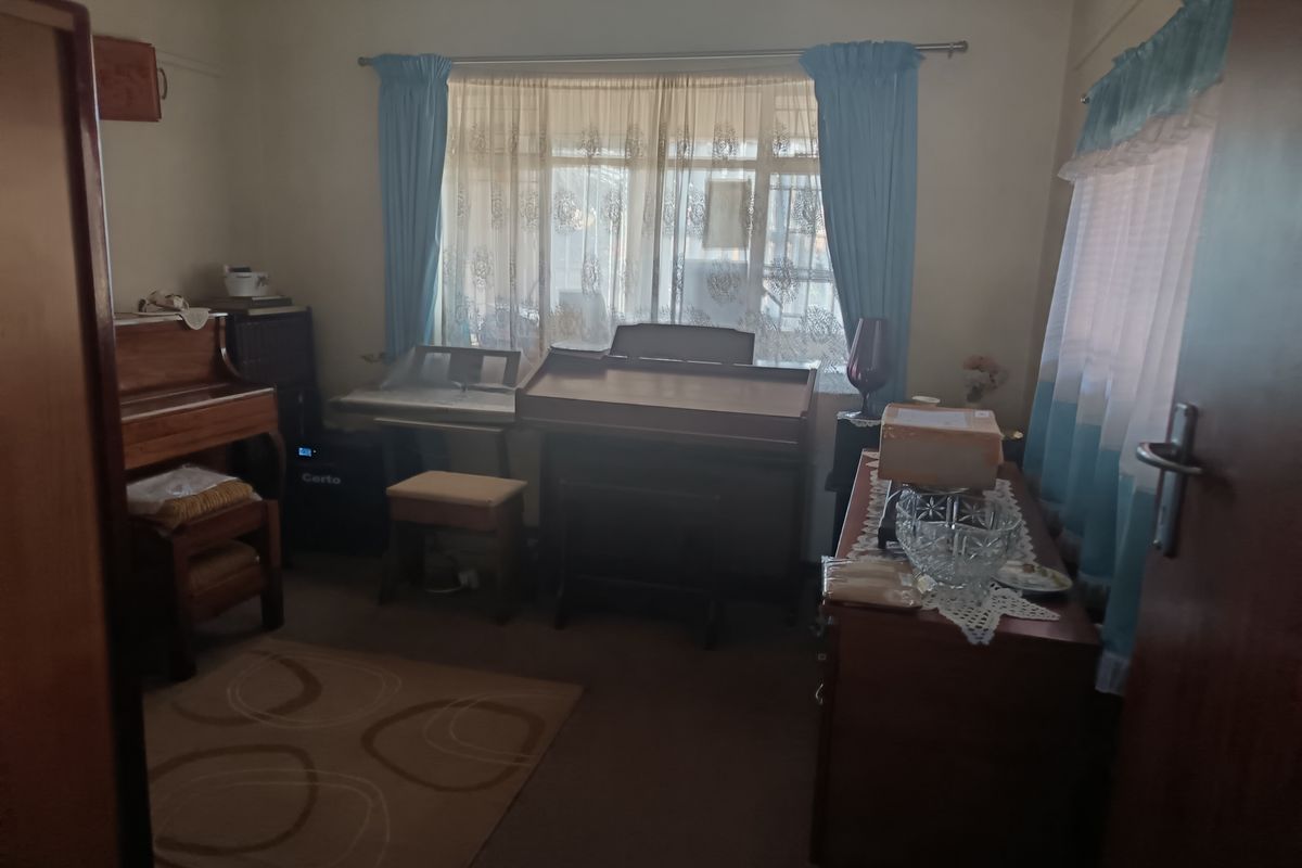 A bedroom featuring neutral walls and window treatments, currently utilized as a music room with various instruments.