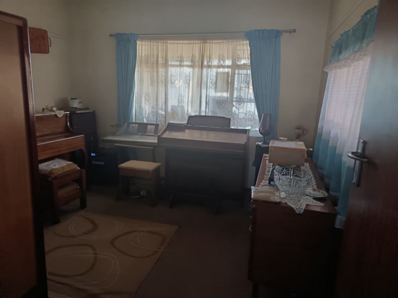A bedroom featuring neutral walls and window treatments, currently utilized as a music room with various instruments.