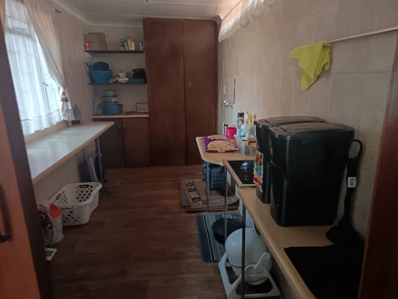 A functional laundry room featuring built-in cabinetry, tiled wall finishes, and durable laminate flooring, providing ample storage and workspace.