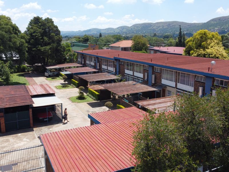 Aerial view of a townhouse complex featuring multiple units with corrugated metal roofs, dedicated carport parking, and paved driveway access.