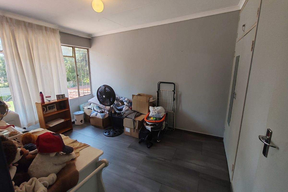 A bedroom featuring built-in cupboards, tiled flooring, and natural light from a window.