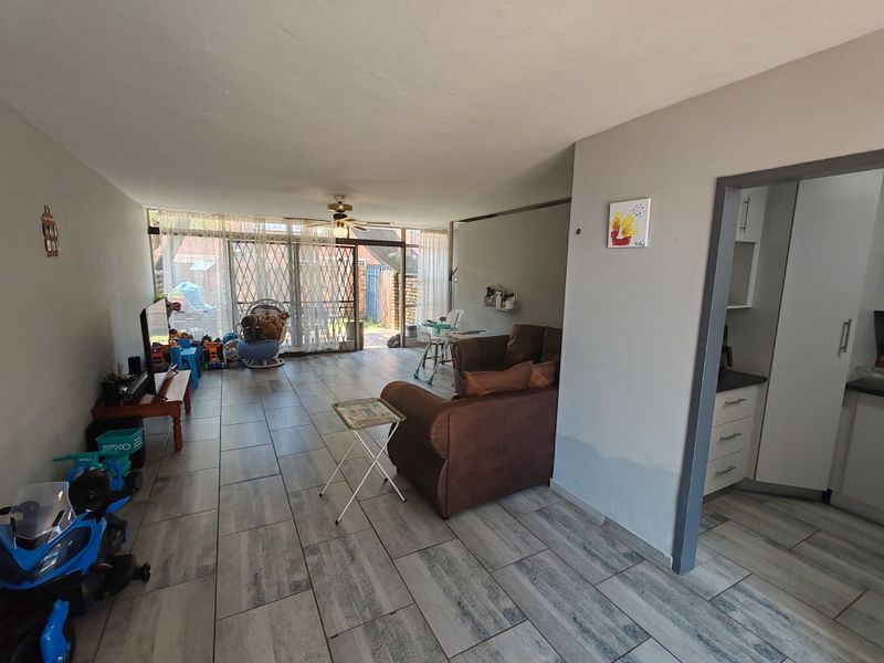 Open plan living area featuring tiled flooring, a ceiling fan, and direct access to the rear patio through a sliding security door.