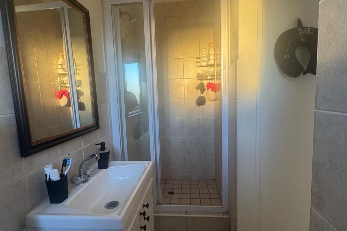 A functional bathroom featuring a vanity cabinet with a basin and a separate shower enclosure with tiled finishes.