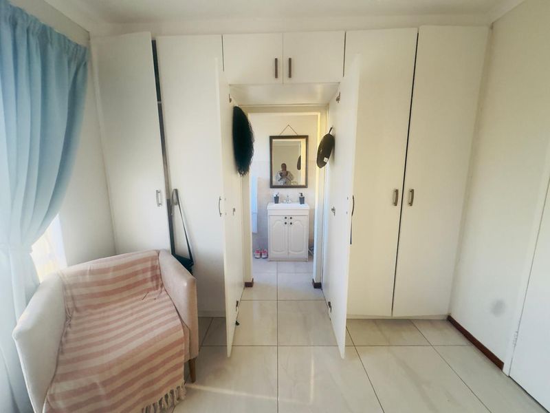 Bedroom featuring extensive built-in cupboard storage and tiled flooring, with a direct view into an adjoining bathroom vanity area.